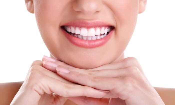 a close up of a woman 's smile with her hands on her chin .