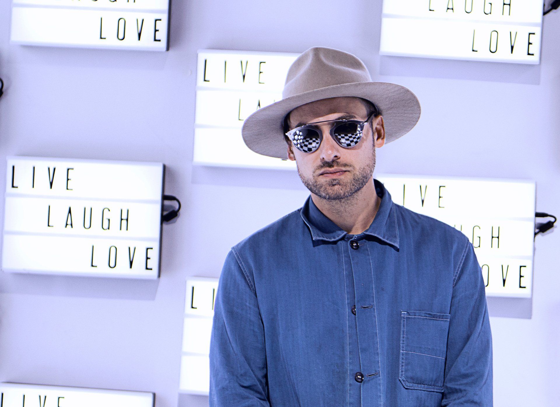 Man in hat and sunglasses poses in front of