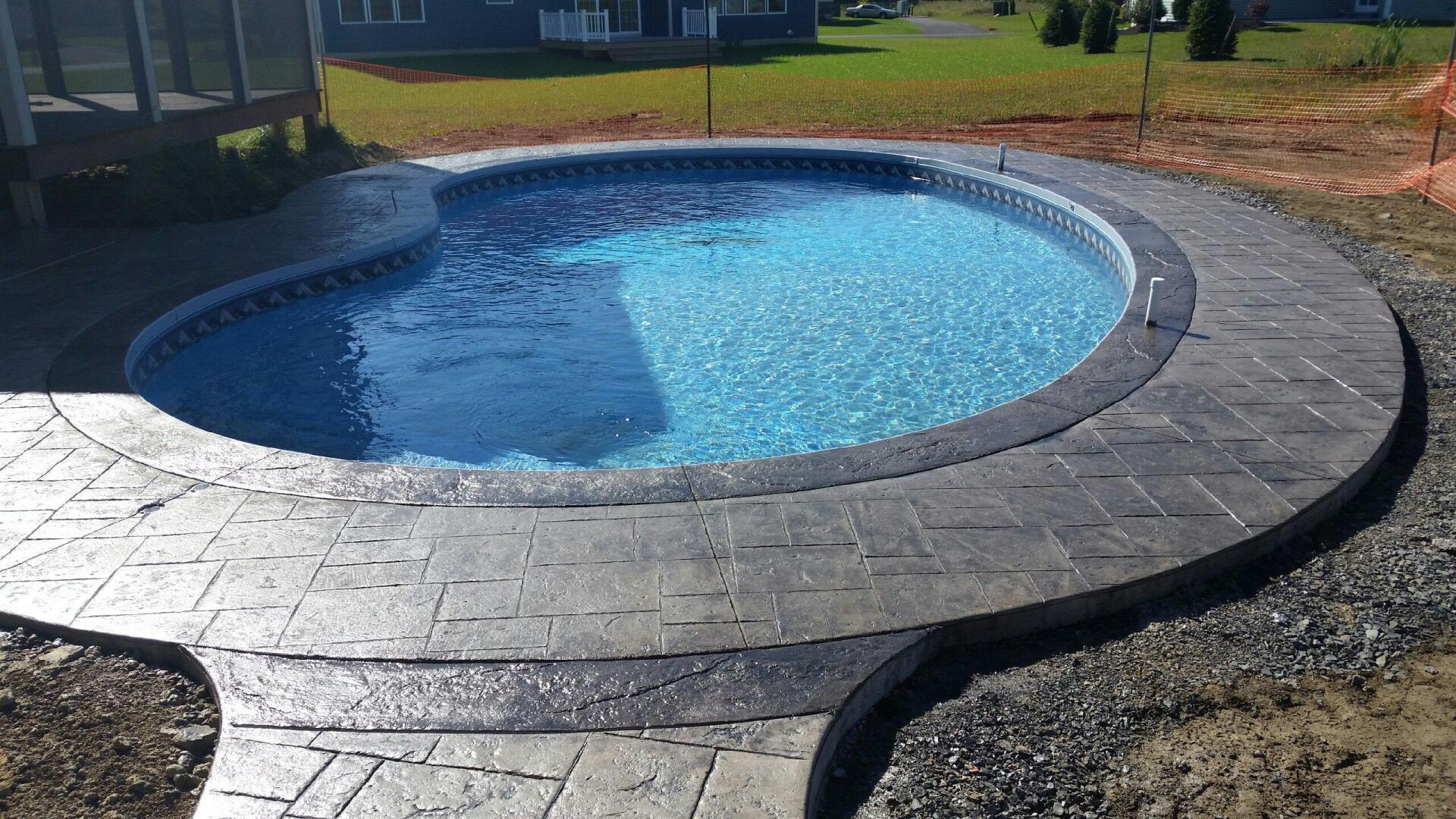 A large swimming pool is surrounded by a concrete patio.