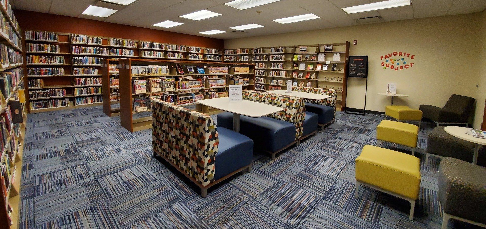A library with a lot of bookshelves and tables and chairs.