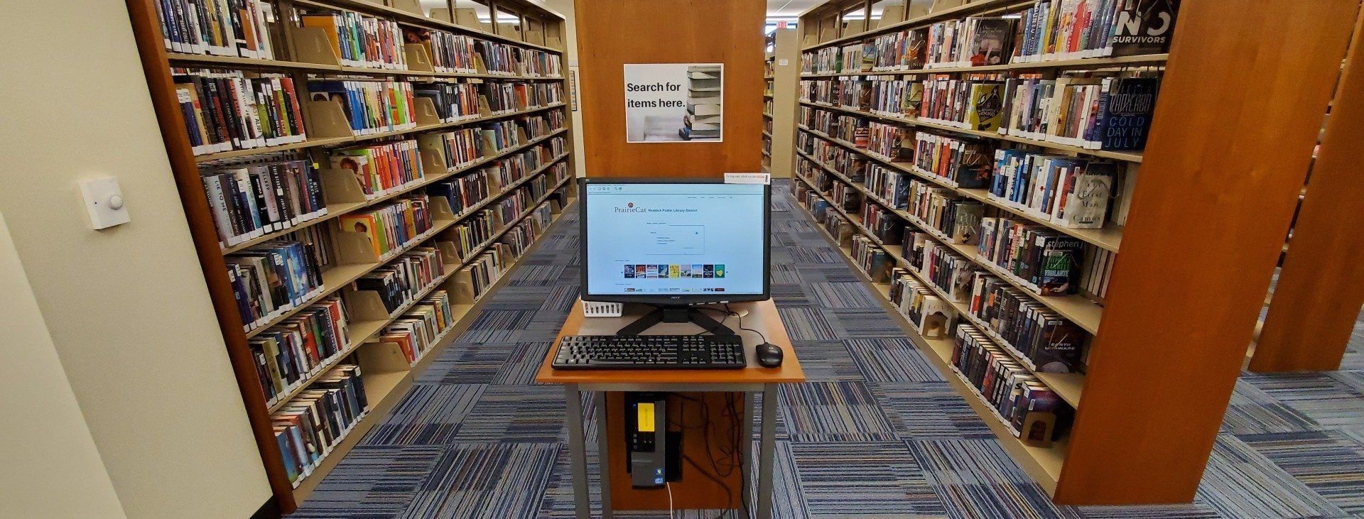 A computer is sitting on a desk in a library.