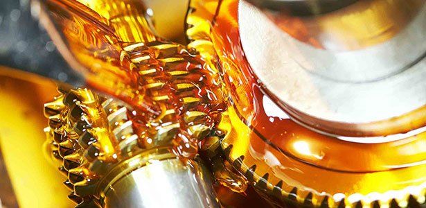 Close-up of shiny metal gears coated in golden oil.