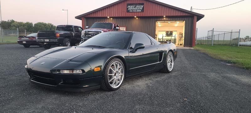 A black sports car is parked in front of a garage.