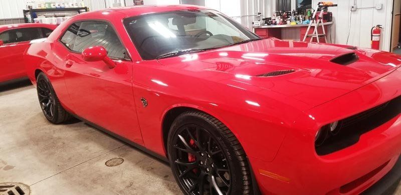 A red dodge challenger is parked in a garage.