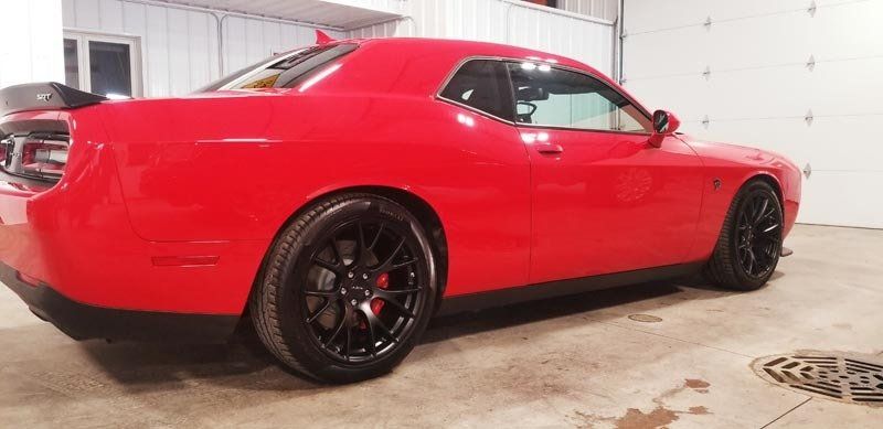 A red dodge challenger is parked in a garage.