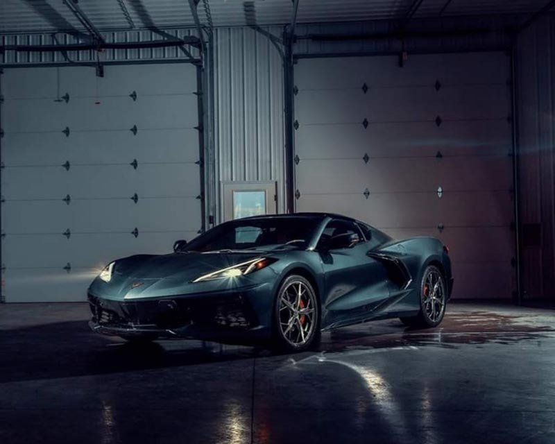 A green sports car is parked in a garage.