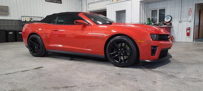 A red convertible car is parked in a garage.