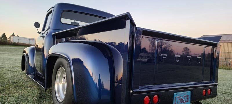 A blue truck is parked in a grassy field.