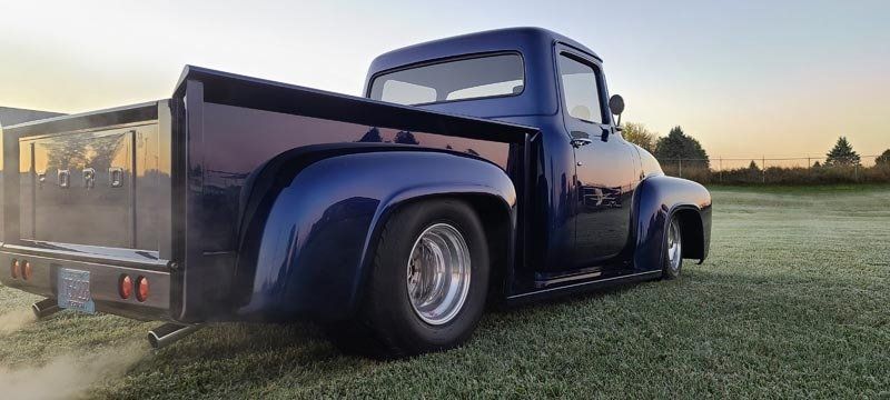 A blue truck is parked in a grassy field.