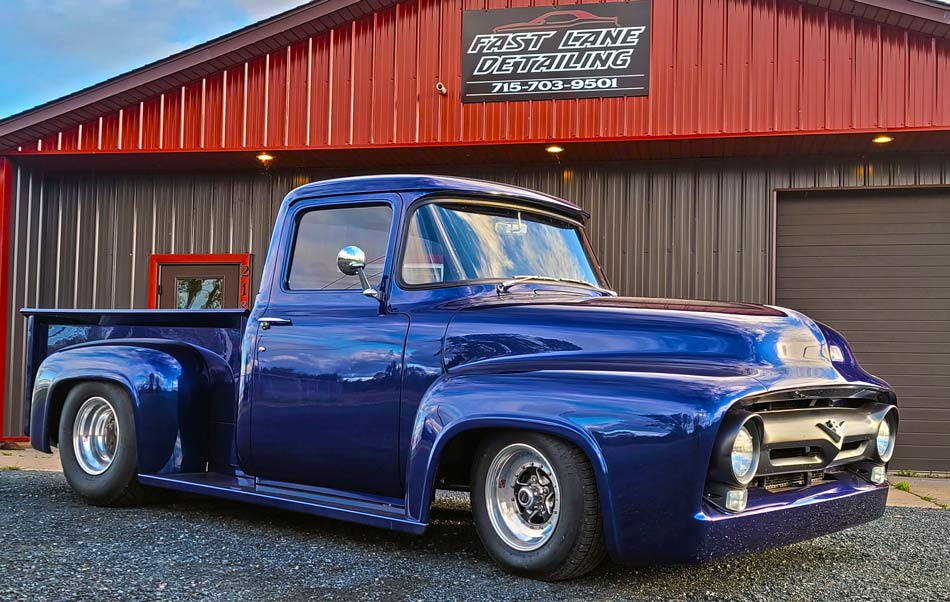 A blue truck is parked in front of a building.
