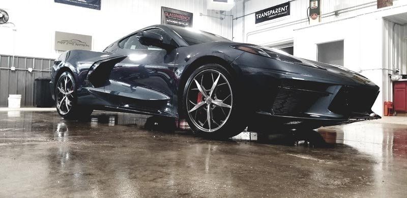A black sports car is parked in a garage.