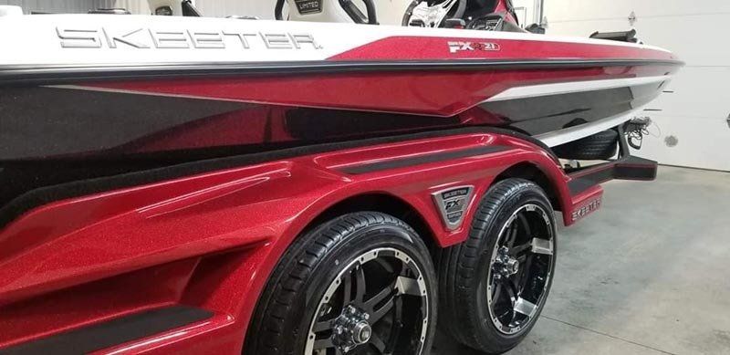 A red and white boat is parked in a garage.