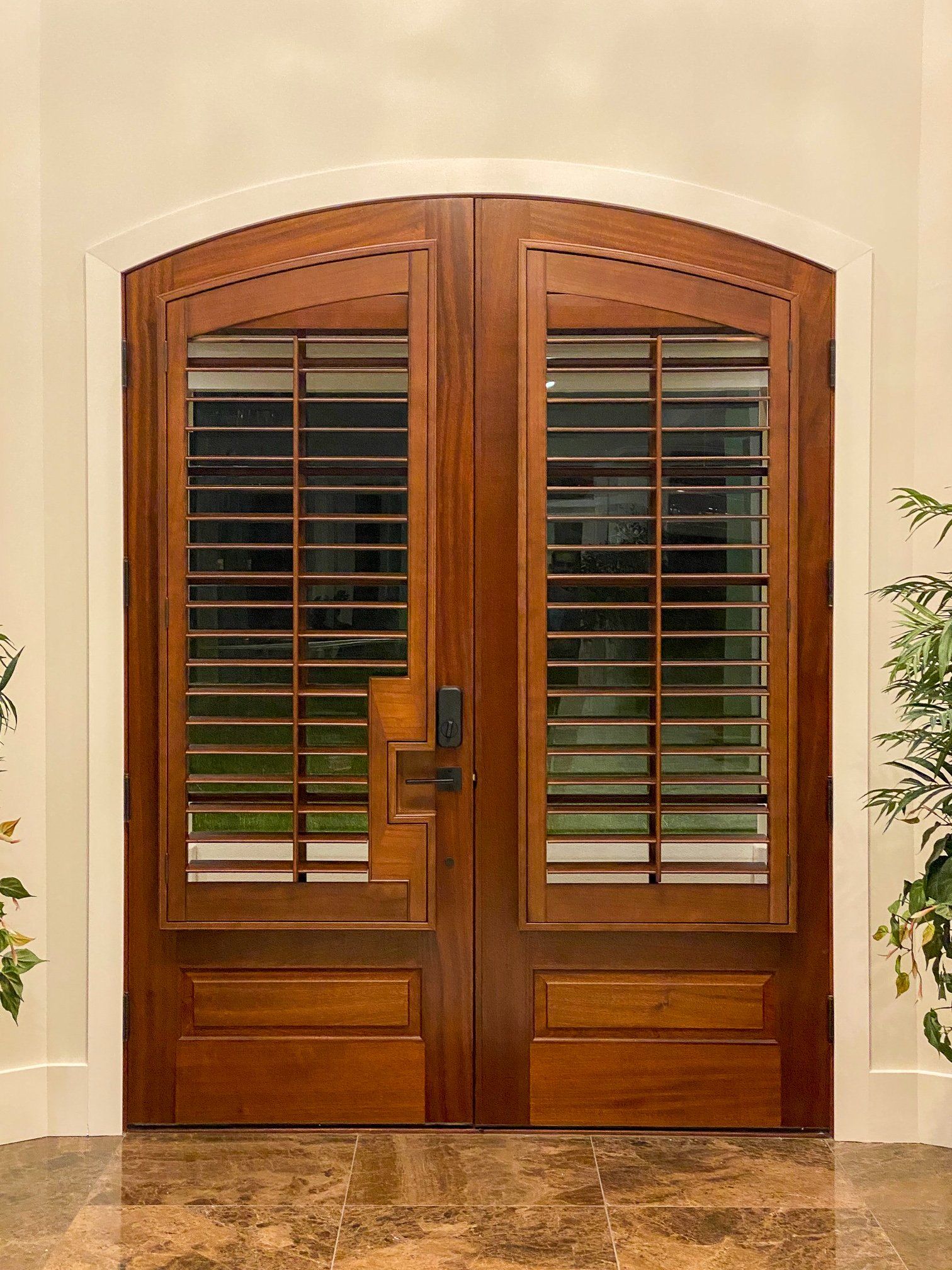 A pair of wooden doors with shutters on them in a room.