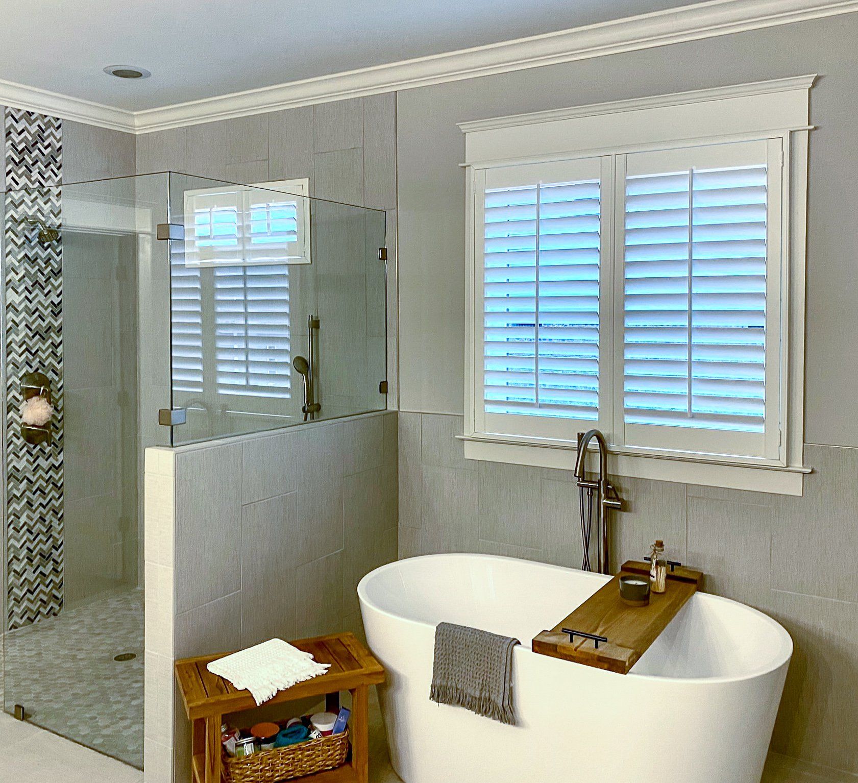 A bathroom with a tub and a shower with shutters on the windows