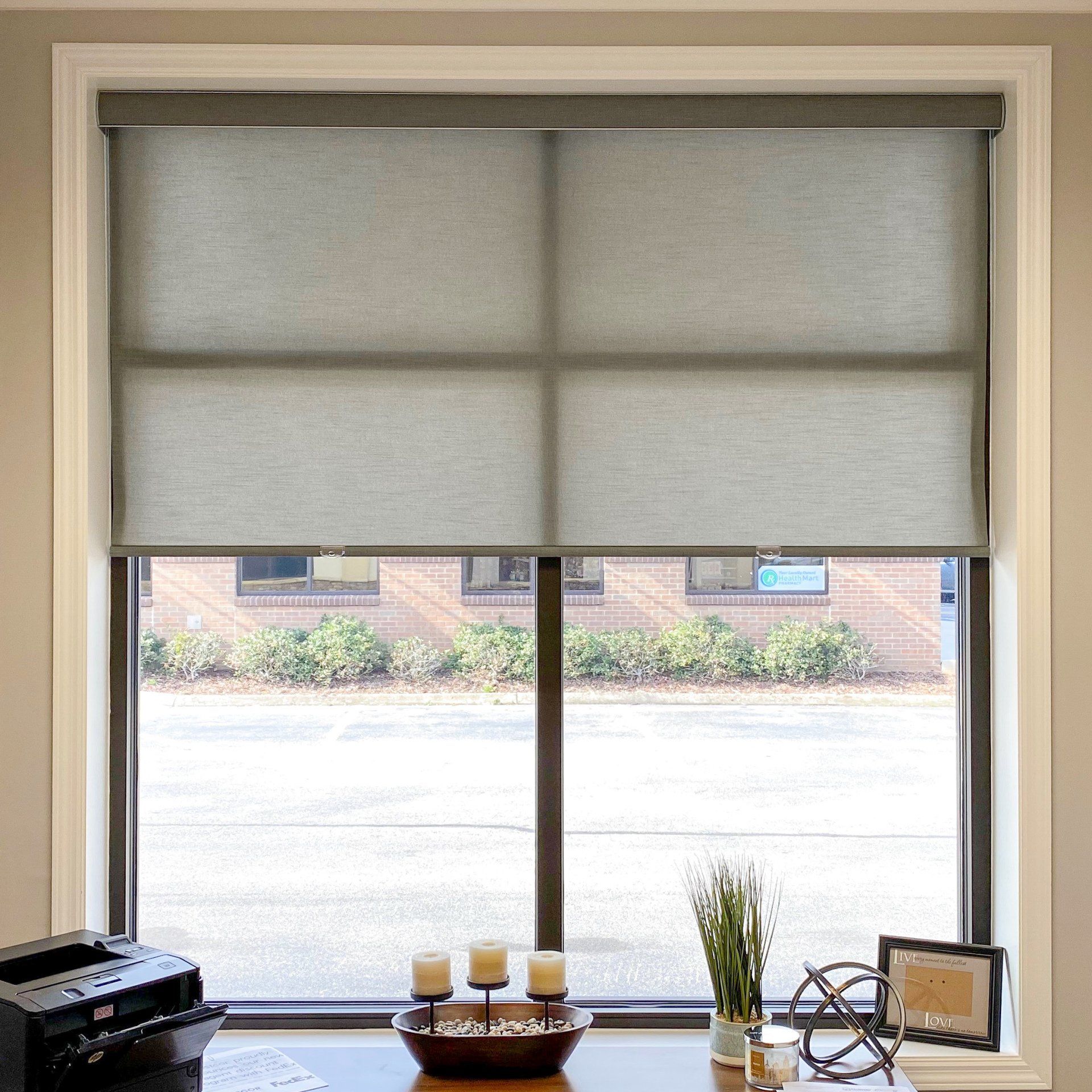A window with a gray blind and a bowl of candles in front of it