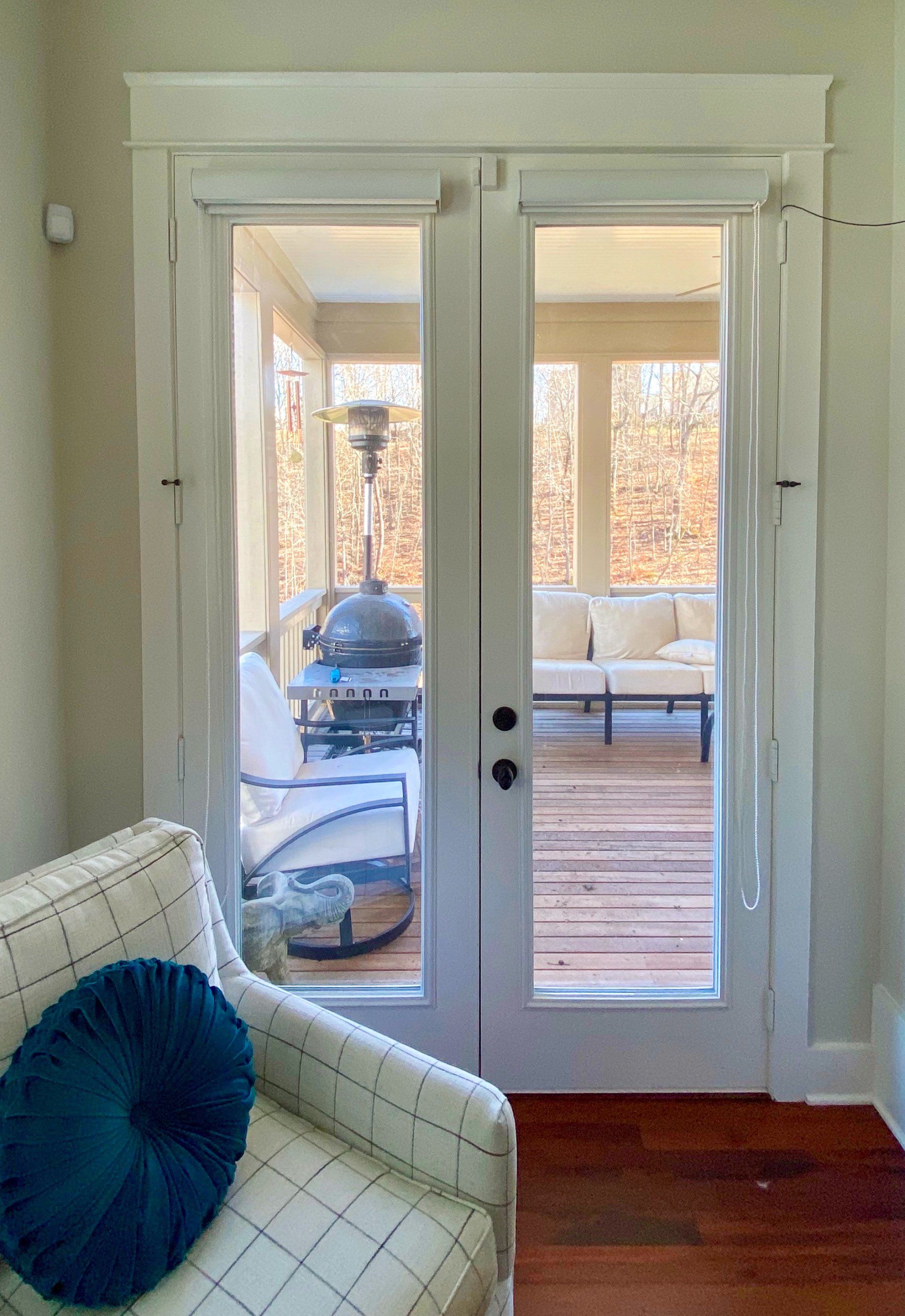 A living room with a chair and a blue pillow looking out to a porch.