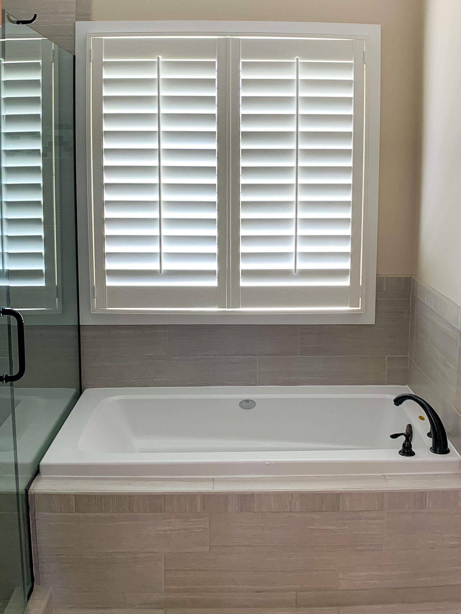 A bathroom with a bathtub and a window with shutters.