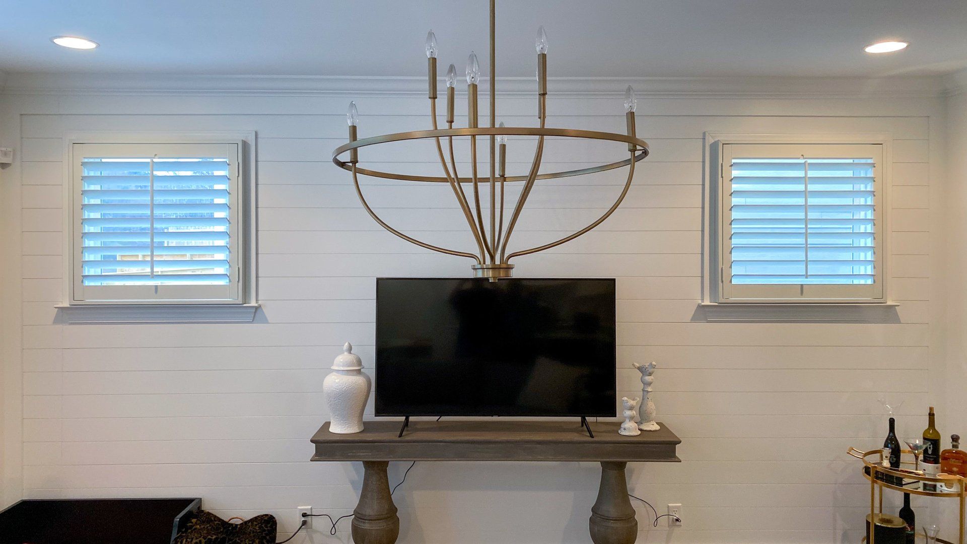 A living room with a television on a mantle and a chandelier hanging from the ceiling.