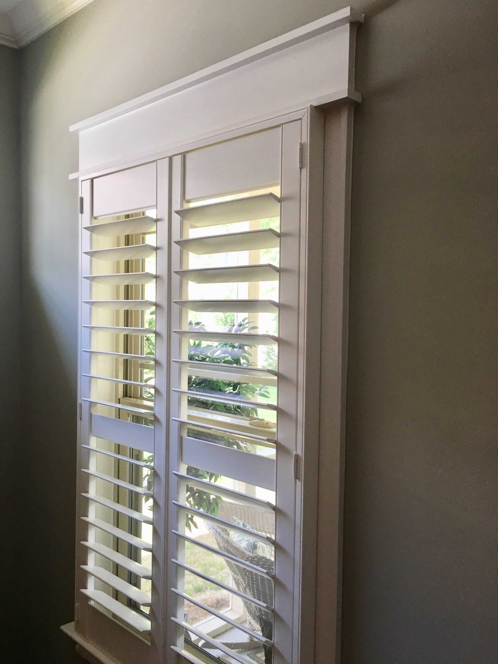 A pair of white shutters on a window in a room.