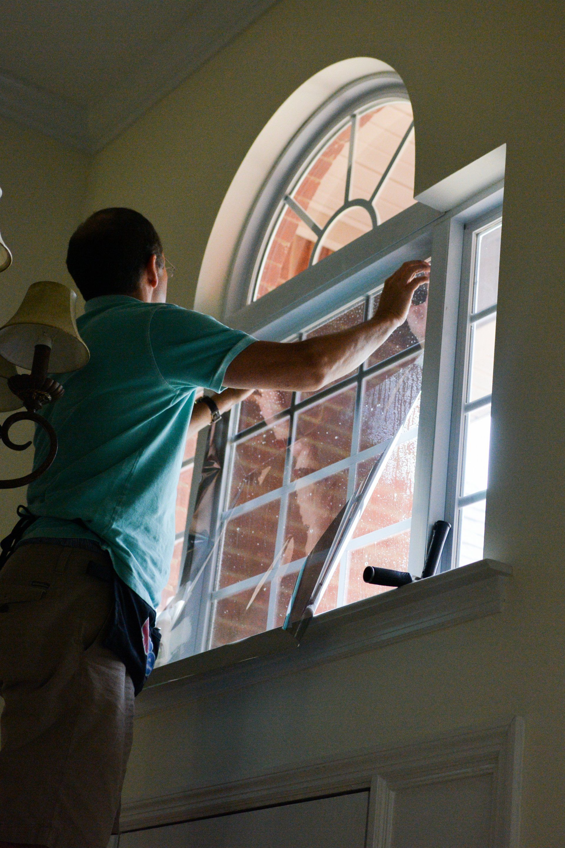 A man in a blue shirt is cleaning a window