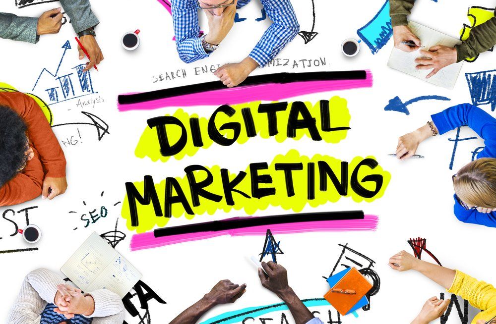 Um grupo de pessoas está sentado ao redor de uma mesa com uma placa que diz marketing digital.