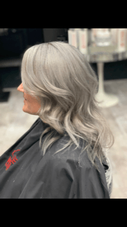 a woman with gray hair is sitting in a chair in a salon .