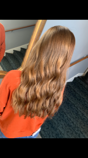 a woman with long brown hair is standing in front of a mirror .