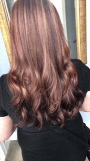 a woman with long brown hair is standing in front of a mirror .