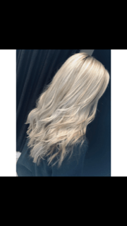 a woman with long blonde hair is standing in front of a black curtain .