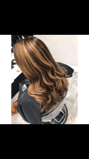 a woman with long brown hair is sitting in a chair in a salon .