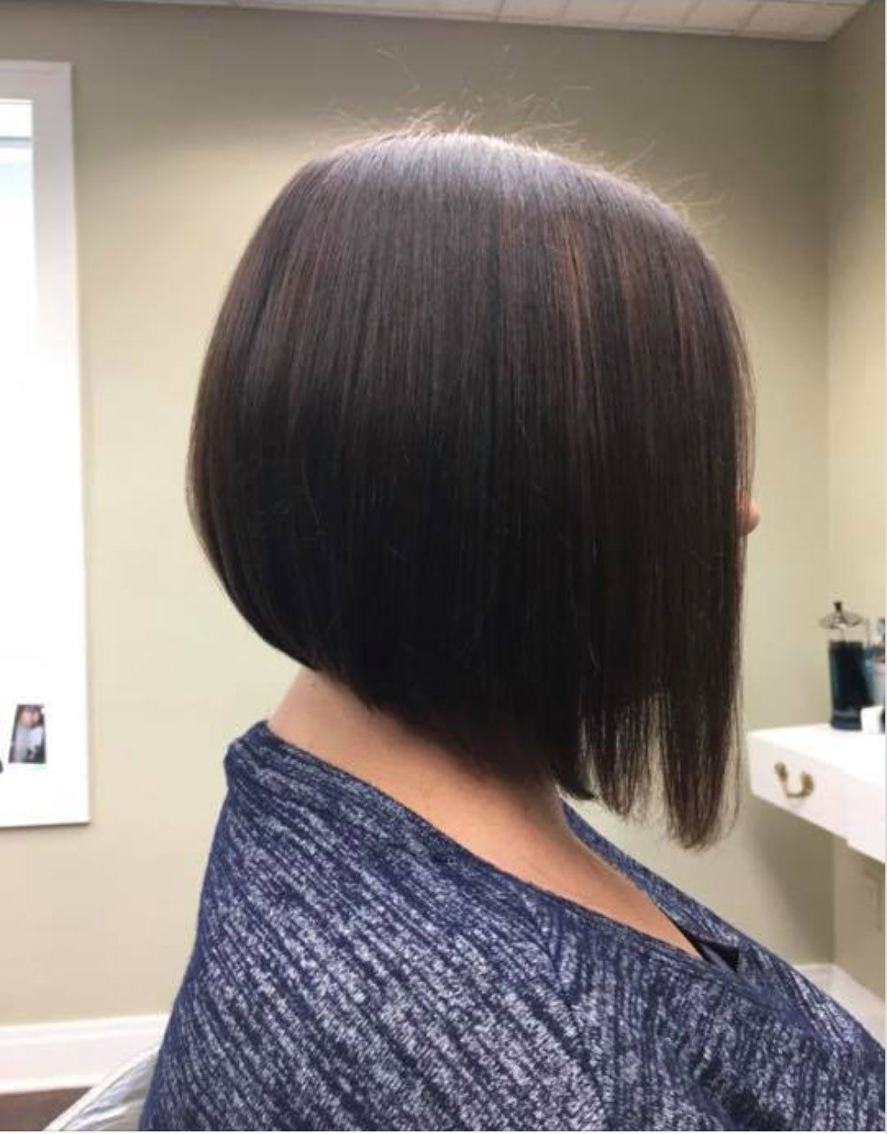 a woman in a blue shirt has her hair cut into a bob
