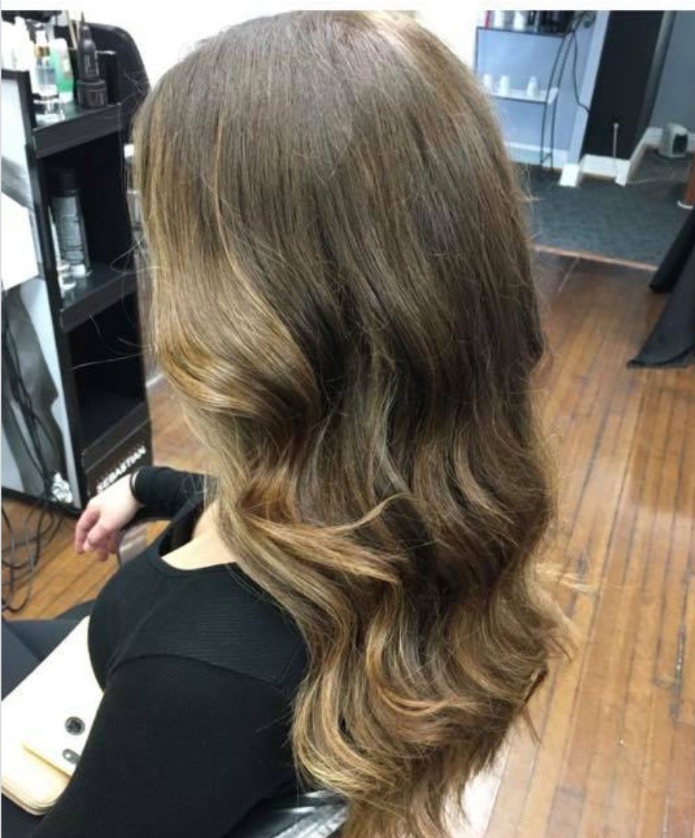 a woman with long brown hair is sitting in a salon chair