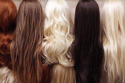a group of wigs of different colors are sitting on a shelf .