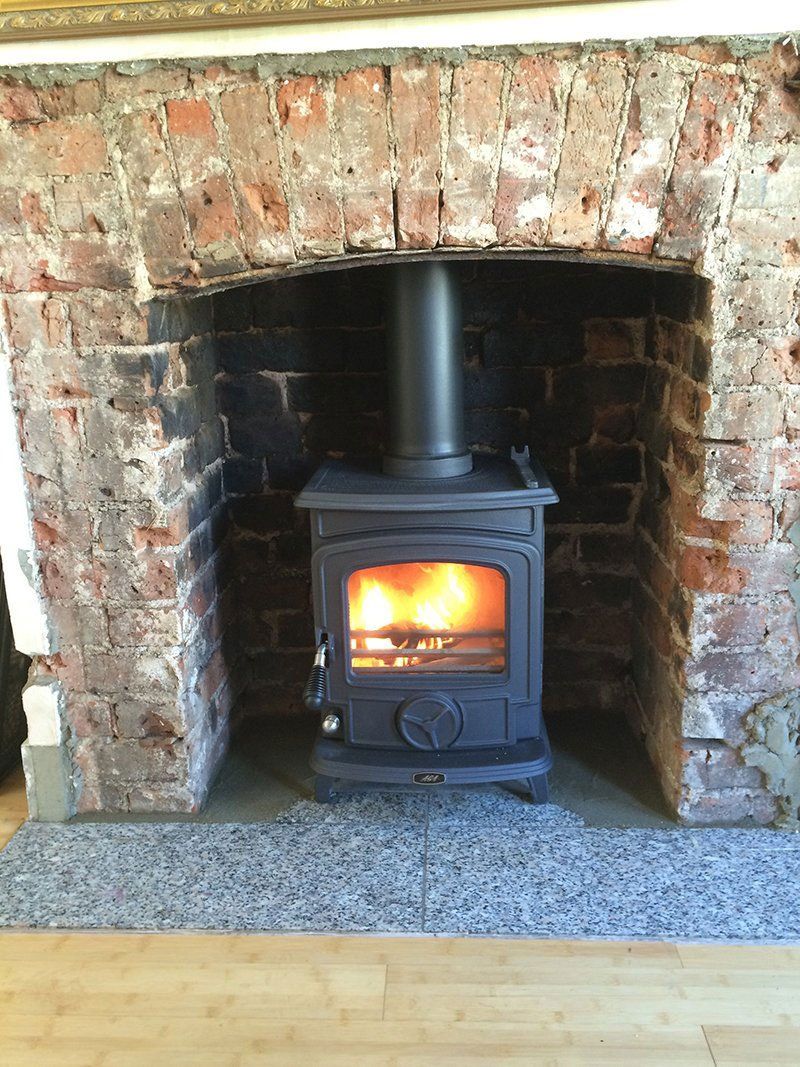 Black stove fitted in a brick fireplace