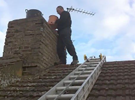 Man on a rood inspecting a chimney pot