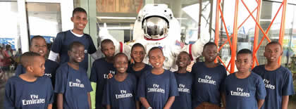 A group of children are posing for a picture in front of a robot.