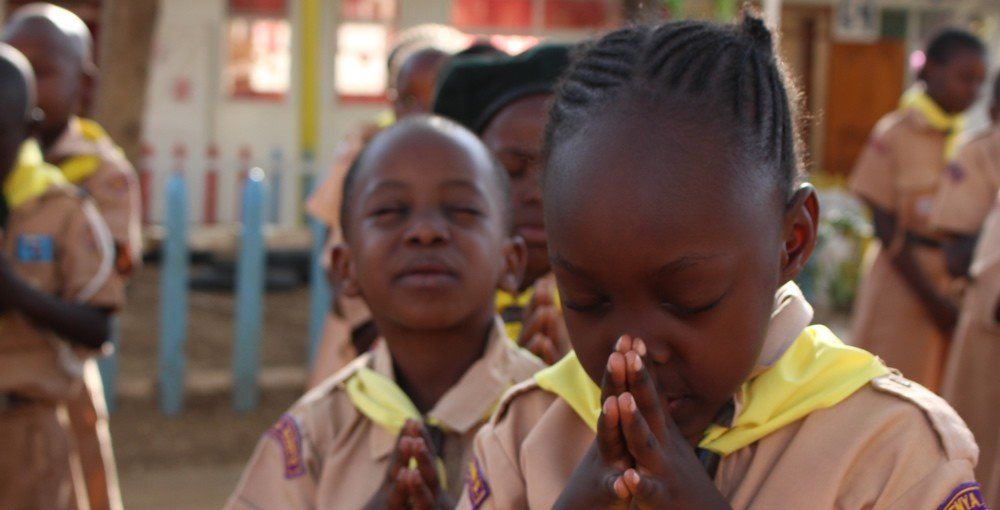 A group of children are praying with their eyes closed