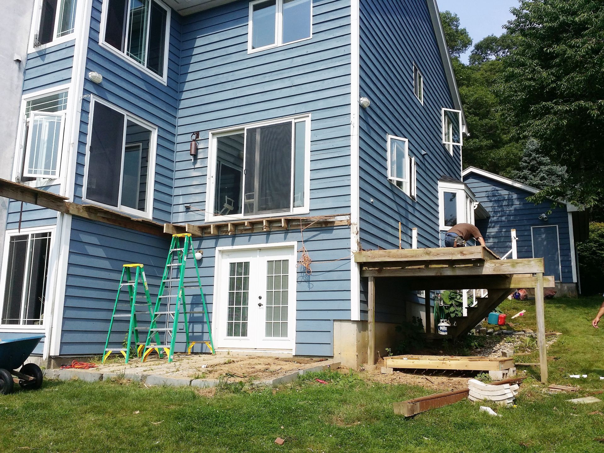 House exterior with blue siding and a deck under construction.