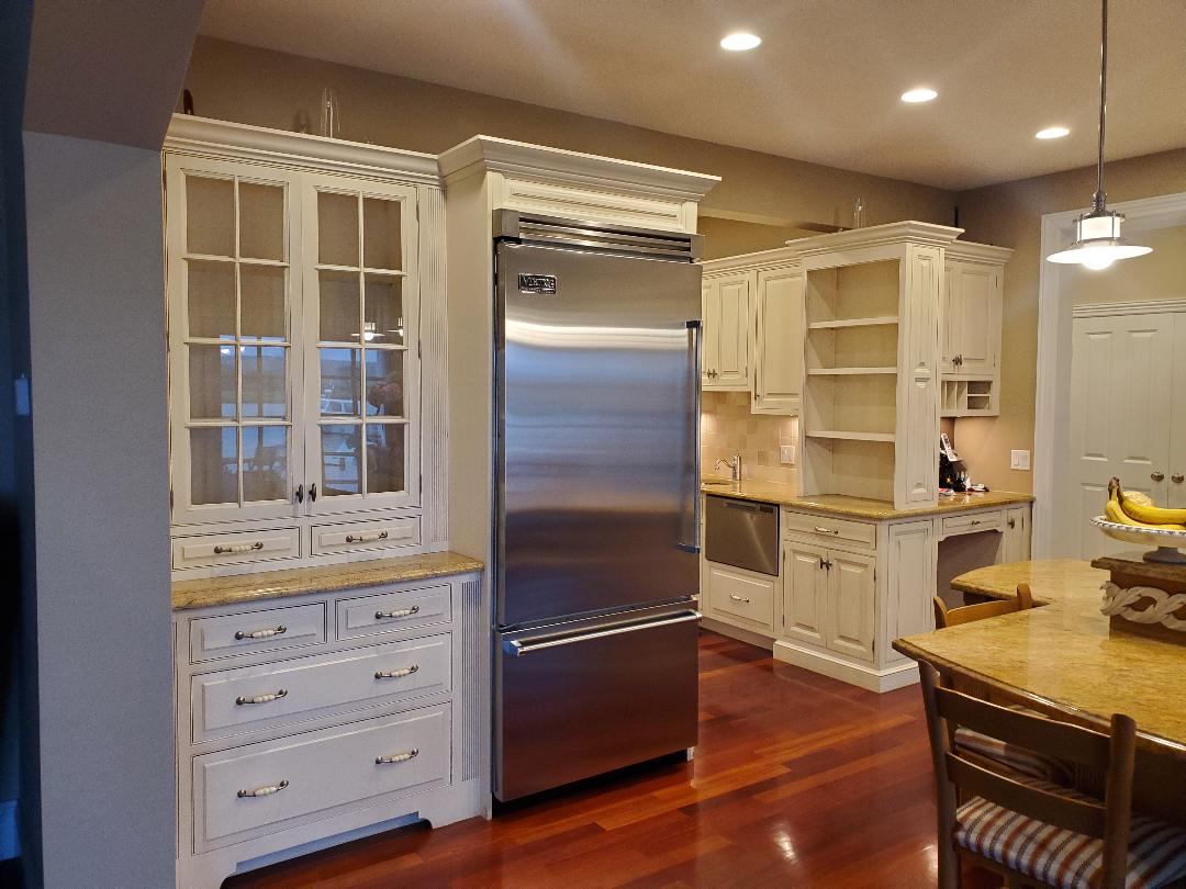 Kitchen with white cabinets, stainless steel refrigerator, granite countertops, and hardwood floors.