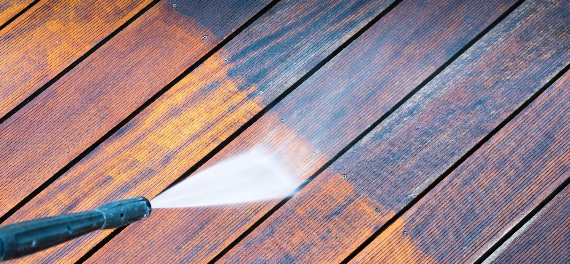 Power washing a wooden deck, showing the effect of cleaning.