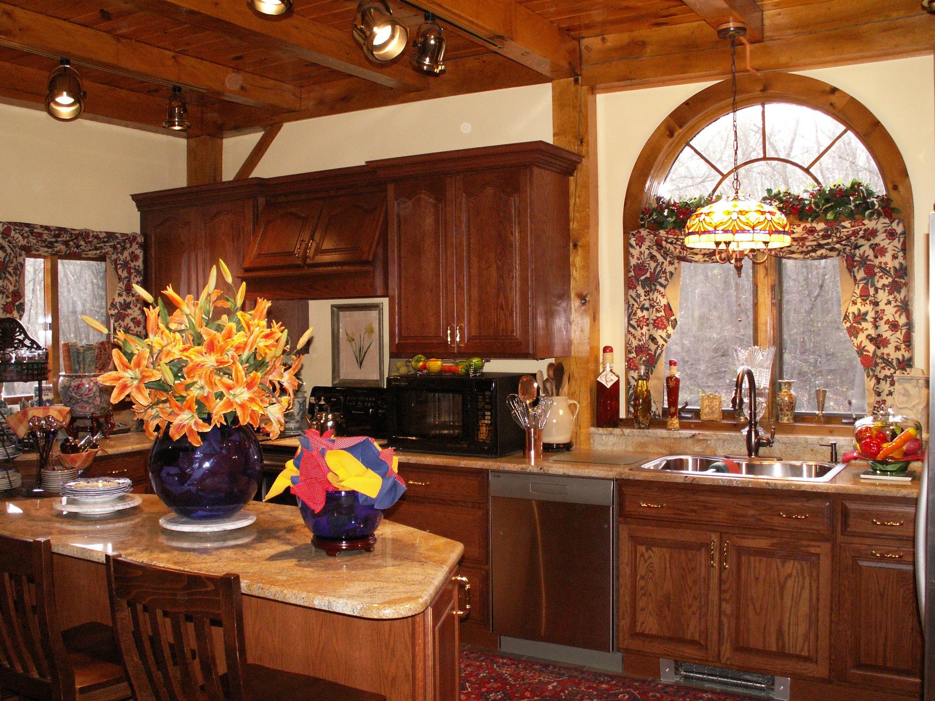 Kitchen with wooden cabinets, granite countertops, and a large arched window.