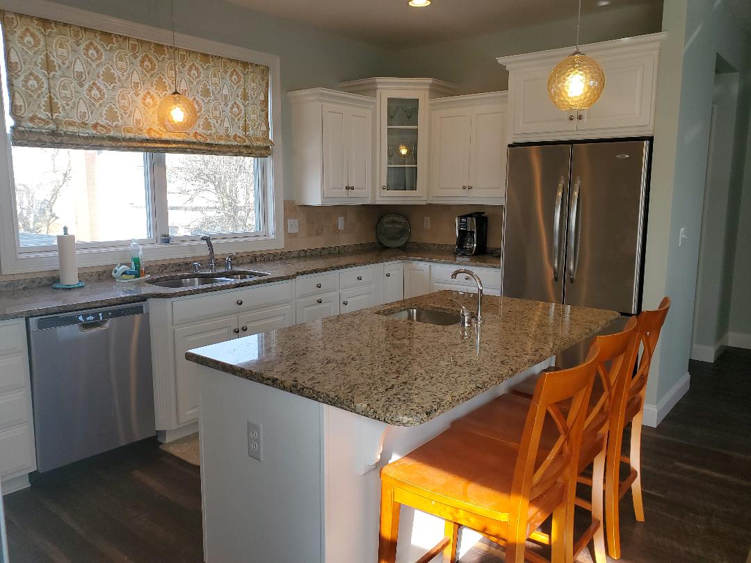 Kitchen with white cabinets, granite countertops, and a kitchen island with stools.