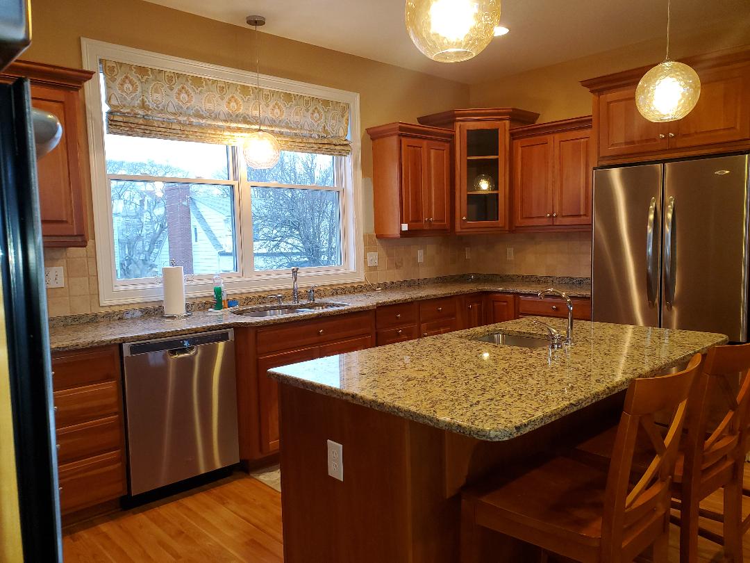 Kitchen with wood cabinets, stainless steel appliances, granite countertops, and an island.
