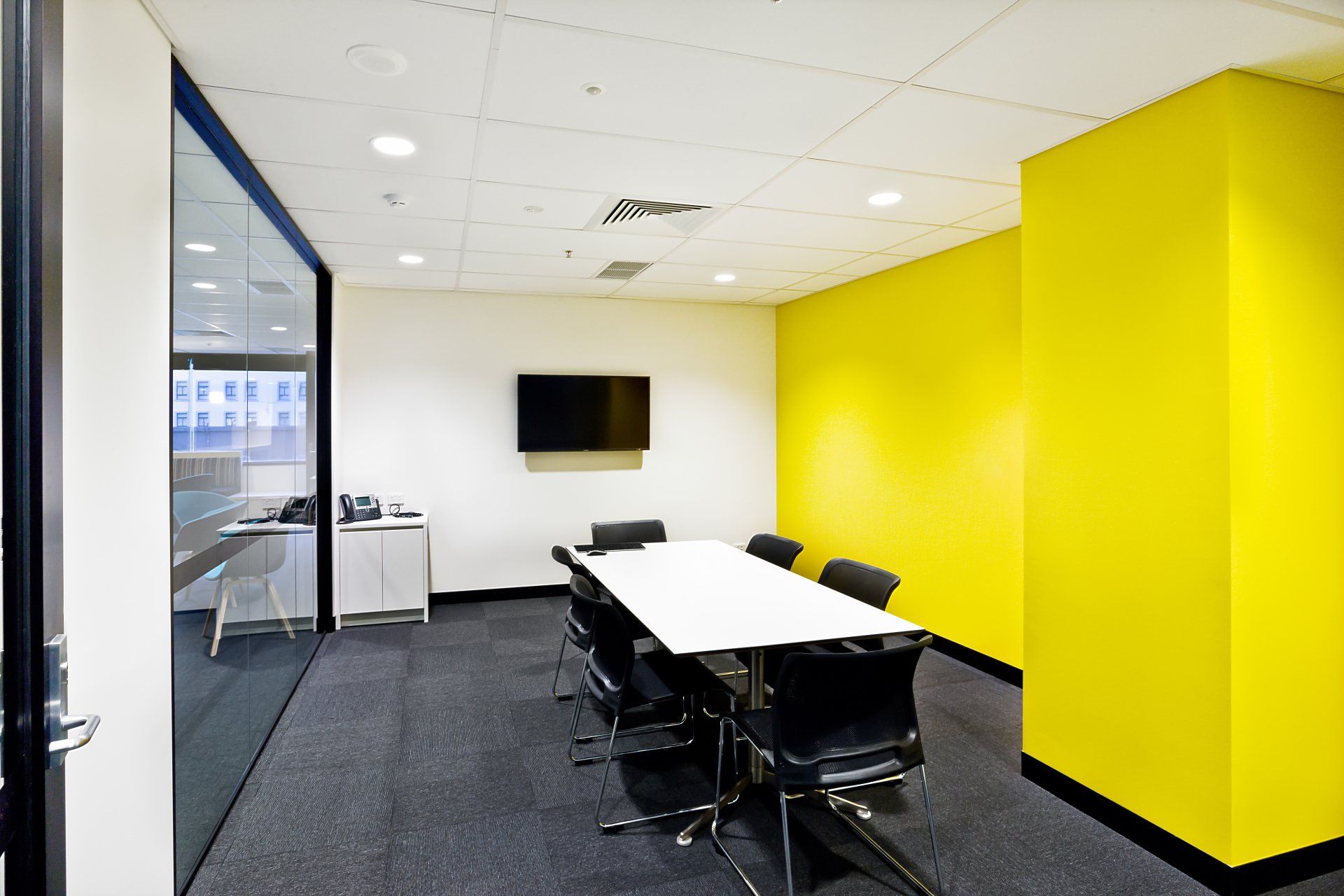 A conference room with yellow walls and a table and chairs