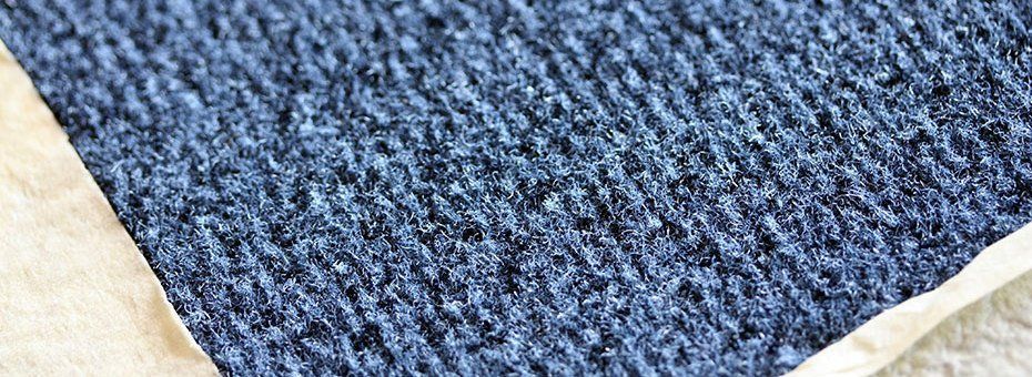 Nahaufnahme eines strukturierten blauen Stoffes vor einem cremefarbenen Rand.