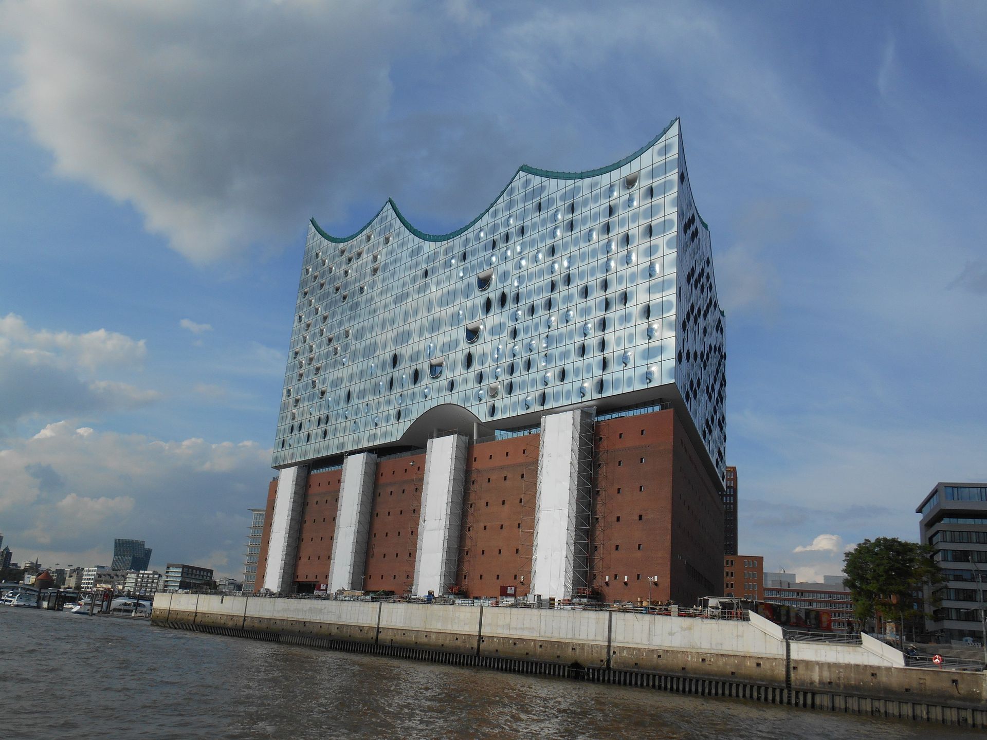 Elbphilharmonie, Konzerthaus in Hamburg, Deutschland; moderne Glas- und Backsteinarchitektur am Wasser, blauer Himmel.