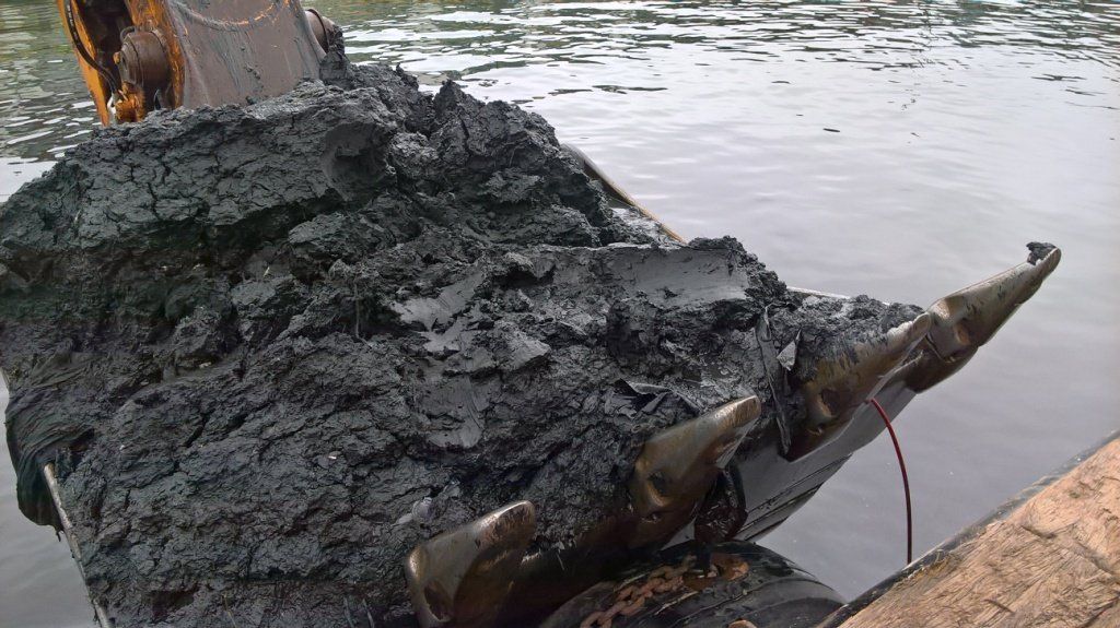 Dunkle, ölverschmierte Trümmer im Wasser. Die Szenerie wirkt verschmutzt und umweltgeschädigt.