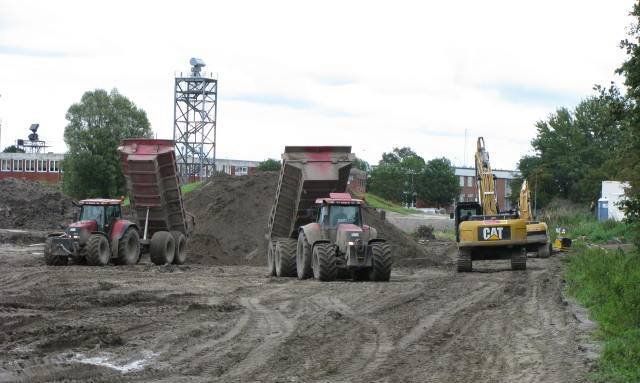 Baustelle: Traktoren kippen Erde ab; Bagger im Schlammbereich.