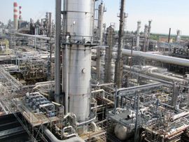 Komplexe Industrieanlage mit zahlreichen Rohren, Türmen und Bauwerken. Bewölkter Himmel.