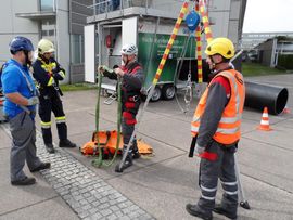 Vier Personen in Schutzausrüstung in der Nähe von Rettungsgeräten. Im Freien, bei einer Rettungsübung.